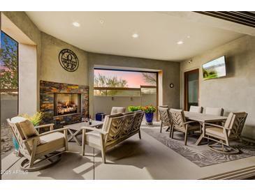 Charming covered patio with fireplace, cozy seating, dining table, and serene outdoor view at 11673 N 136Th St # 1019, Scottsdale, AZ 85259