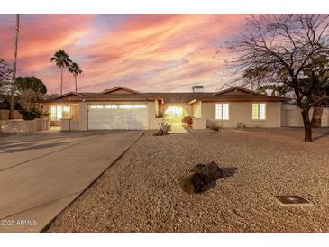 Charming ranch-style home featuring a two-car garage and desert landscaping, set against a vibrant sunset sky at 14013 N 57Th Pl, Scottsdale, AZ 85254