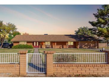Charming brick home with a well-maintained front yard and inviting red double-door entrance at 14251 N 182Nd Ave, Surprise, AZ 85388