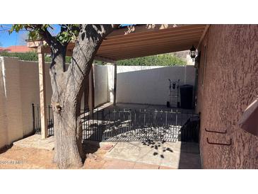 Covered patio with mature tree, fenced area, and neutral-toned stucco walls at 15601 N 27Th St # 5, Phoenix, AZ 85032