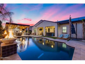 Inviting backyard with a sparkling pool, covered patio, outdoor kitchen, and comfortable lounge seating at 20125 E Via Del Rancho --, Queen Creek, AZ 85142