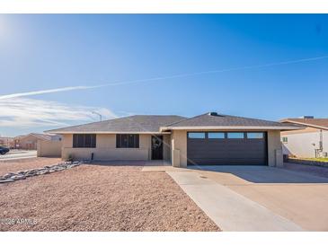 Charming single-story home featuring a well-maintained front yard, and a dark colored two car garage at 2641 E Garnet Ave, Mesa, AZ 85204