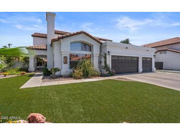 Charming single-story home featuring a tile roof, a three-car garage, and a well-manicured lawn at 1233 E Azure Sea Ln, Gilbert, AZ 85234