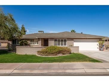 Charming single-story brick home with a manicured lawn and a spacious two-car garage on a sunny day at 1506 E Gemini Dr, Tempe, AZ 85283