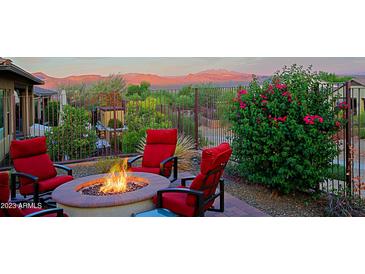 Inviting back patio with a stone fire pit, plush red chairs, and stunning mountain views at 17913 E Vista Desierto --, Rio Verde, AZ 85263