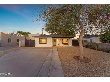 Charming single-story home with a desert landscape, quaint bench, and bright blue-green front door at 2209 N 23Rd St, Phoenix, AZ 85006