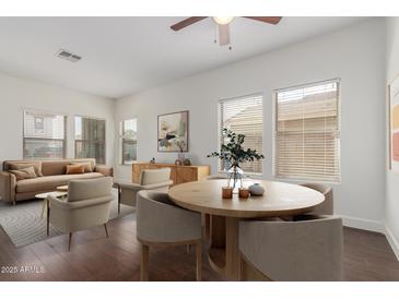 Bright living room featuring hardwood floors, tan-colored furniture, dining table, and recessed lighting at 25792 W Burgess Ln, Buckeye, AZ 85326