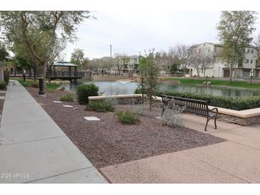 Scenic community pond with bridge, fountain and walking path, surrounded by lush landscaping and residential buildings at 2670 S Voyager Dr # 108, Gilbert, AZ 85295