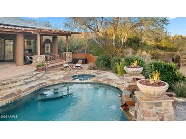 Beautiful backyard pool with stone accents, spa, waterfall, and outdoor seating for relaxation at 27641 N 74Th St, Scottsdale, AZ 85266