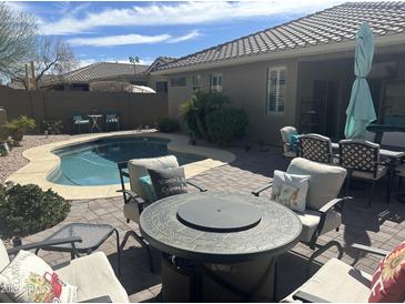 Inviting backyard pool area featuring a cozy fire pit and comfortable patio furniture at 39743 N High Noon Way, Anthem, AZ 85086