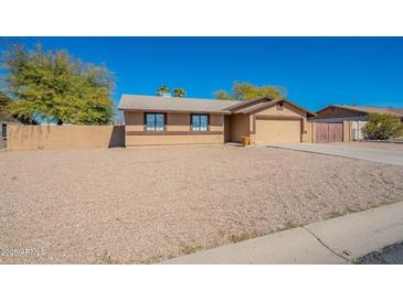 Tan single-story home with desert landscaping and an attached two-car garage at 516 E Mesquite Ave, Apache Junction, AZ 85119