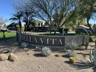 Welcoming sign reading 'Bella Vita' with desert landscaping and condo buildings in the background on a sunny day at 5995 N 78Th St # 2026, Scottsdale, AZ 85250