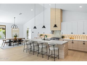 Bright, modern kitchen with island seating, stainless steel appliances, and stylish light fixtures at 6313 N 10Th Dr, Phoenix, AZ 85013