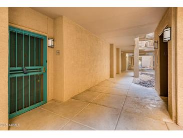 Hallway featuring a secure teal door and textured walls illuminated by modern sconces at 14950 W Mountain View Blvd # 4103, Surprise, AZ 85374