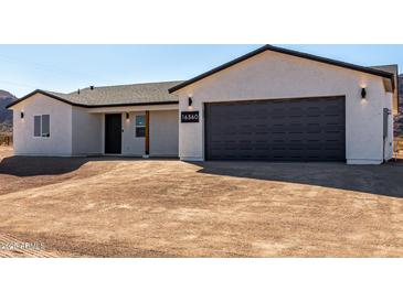 Classic single-story home featuring white stucco siding, dark trim and a gray garage door at 16560 N Slate Ln, Maricopa, AZ 85139