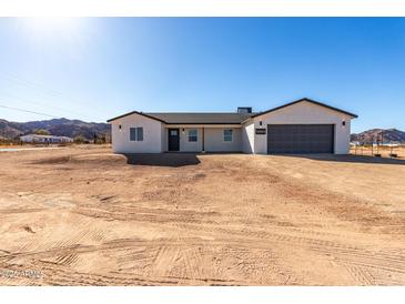 Newly constructed single-story home featuring stucco siding, dark trim and a gray garage door at 16560 N Slate Ln, Maricopa, AZ 85139