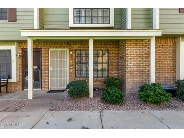 Charming townhouse featuring a brick facade, complemented by lush green bushes and decorative rock landscaping at 4842 E Kachina Trl # 3, Phoenix, AZ 85044