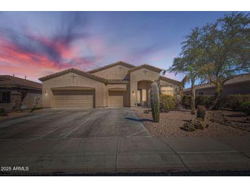 Charming, one-story stucco home featuring a three-car garage and desert landscaping at sunset at 9590 W Bajada Rd, Peoria, AZ 85383