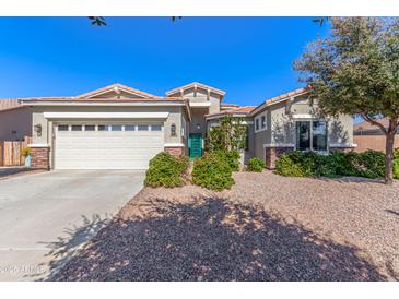 Charming home showcasing a lush landscaped yard, an attached garage, and a decorative front door at 3020 E Tiffany Way, Gilbert, AZ 85298