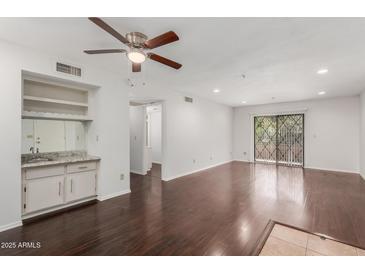 Bright living room with dark hardwood floors, built-in bar, and sliding glass doors to the outside at 7777 E Main St # 258, Scottsdale, AZ 85251