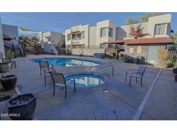 Community pool and spa with outdoor kitchen and seating area for relaxing in the sun at 4120 N 78Th St # 217, Scottsdale, AZ 85251