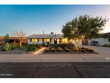 Charming single-story home with a well-manicured front yard and desert landscaping at dusk at 8443 E Sheridan St, Scottsdale, AZ 85257