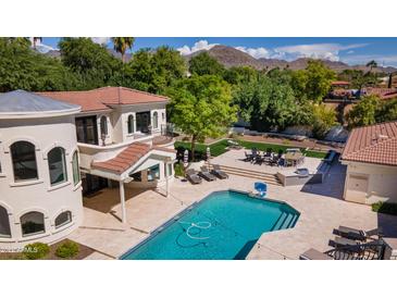 Expansive backyard oasis features a sparkling pool, dining area, and mature landscaping at 10440 E Larkspur Dr, Scottsdale, AZ 85259