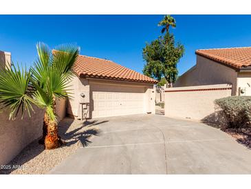 Attached home featuring a two-car garage, tile roof, desert landscaping, private gate, and ample driveway space at 11210 N 109Th St, Scottsdale, AZ 85259