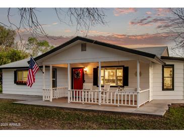 Charming home featuring a covered front porch, white siding, and an inviting red door at 17335 W Cheryl Dr, Waddell, AZ 85355