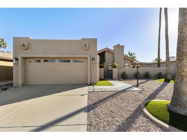 Beige single-story home with two-car garage, palm trees, a concrete driveway, and manicured desert landscaping at 25821 S Hollygreen Dr, Sun Lakes, AZ 85248