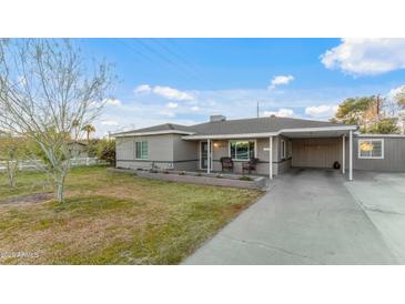 Charming single-story home with well-manicured lawn, covered front porch, and attached carport at 6704 N 10Th Pl, Phoenix, AZ 85014