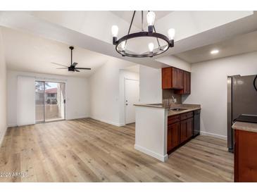 Open-concept living room boasts wood floors, fan, and sliding doors to a balcony, flowing to an updated kitchen with a breakfast bar at 10610 S 48Th St # 2001, Phoenix, AZ 85044