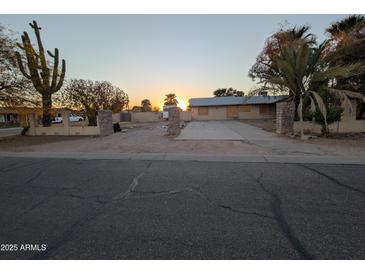 Single-story home with a long driveway, desert landscaping, and sunset views at 150 N 65Th St, Mesa, AZ 85205