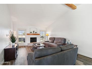 Bright living room features a fireplace, wood beam accent, and wood laminate flooring at 4530 W Continental Dr, Glendale, AZ 85308