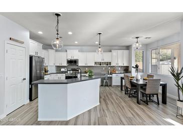 Modern kitchen with white cabinets, stainless steel appliances, and an island with bar seating at 1835 E Bartlett Pl, Chandler, AZ 85249
