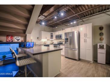 Bright kitchen features stainless steel appliances, white cabinetry, and an island with bar stool seating at 2 W Georgia Ave # 5, Phoenix, AZ 85013