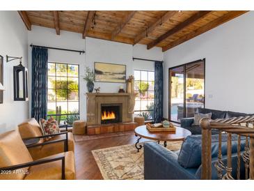 Inviting living room with a stone fireplace, wood beam ceilings, hardwood floors, and comfortable seating at 2548 E Vermont Ave, Phoenix, AZ 85016