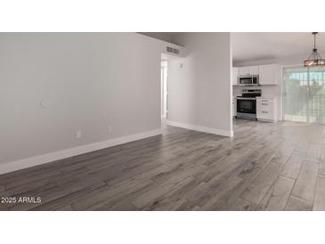 Bright living room features modern gray floors, white trim, and plenty of natural light at 3120 N 67Th Ln # 96, Phoenix, AZ 85033