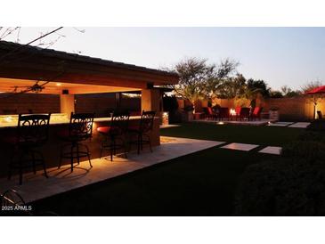 Outdoor oasis with a bar, fire pit, and ample seating for entertainment in backyard at 31626 N 129Th Dr, Peoria, AZ 85383