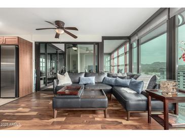 Stylish living room with hardwood floors, sectional sofa, and sliding doors to enclosed patio at 4808 N 24Th St # 1402, Phoenix, AZ 85016