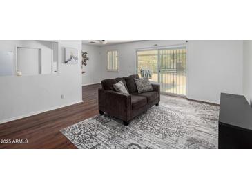 Bright living room featuring wood floors, a patterned rug, and sliding doors to the outside patio at 7327 N 21St Ave, Phoenix, AZ 85021