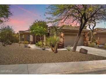 Charming single-story home with desert landscaping and a stone-accented facade, blending with the natural surroundings at 7435 E Quien Sabe Way, Scottsdale, AZ 85266