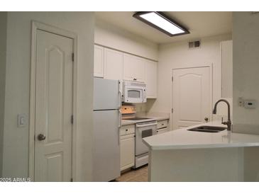 A bright kitchen has white cabinets, a white countertop and appliances at 1701 E Colter St # 191, Phoenix, AZ 85016