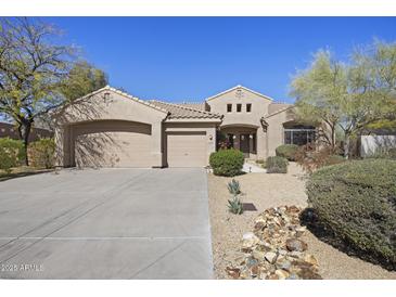 Charming single-story home featuring desert landscaping, a three-car garage, and a welcoming front entrance at 28604 N 92Nd Pl, Scottsdale, AZ 85262