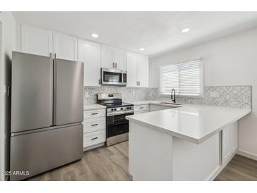 Modern kitchen with stainless steel appliances, white cabinets and countertops, and decorative backsplash at 6173 N Granite Reef Rd, Scottsdale, AZ 85250