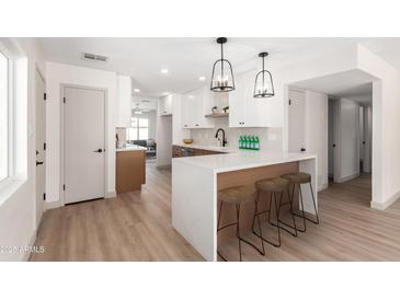 Bright kitchen features a large island with seating, white cabinets, and modern pendant lighting at 8732 E Forest Dr, Scottsdale, AZ 85257