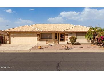 Charming single-story home showcasing a well-manicured front yard with lush landscaping and a two-car garage at 10856 E Kiva Ave, Mesa, AZ 85209