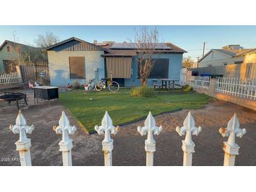 Cozy backyard featuring a well-kept lawn, patio furniture, and charming white picket fence at 1434 E Roosevelt St, Phoenix, AZ 85006