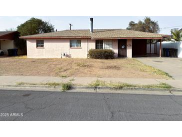 Street-level shot of single story home with pink brick and brown roof at 1466 E Nielson Ave, Mesa, AZ 85204