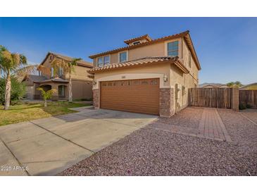 Stunning two-story home featuring a brown garage door, stone accents, a long driveway and desert landscaping at 3127 W Apollo Rd, Phoenix, AZ 85041